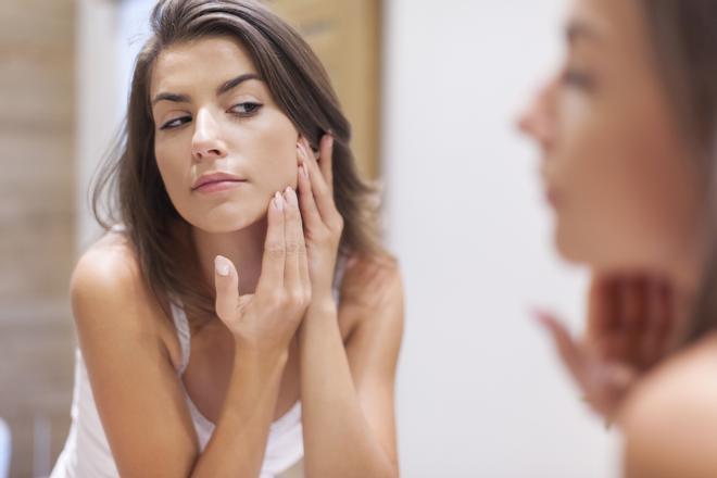 Mujer mirando su piel en el espejo