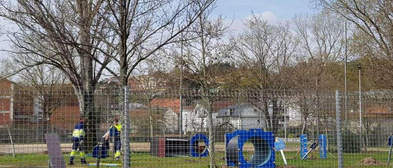 Arriba, instalación, ayer, de los elementos del circuito de agility. Izquierda, el perímetro del parque se cerró a principios de esta semana. // Gonzalo Núñez