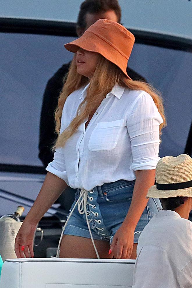 Beyonce con shorts vaqueros, camisa blanca y goroo de pescador