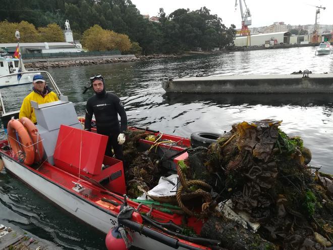 Dos trabajadores transportan en una embarcación residuos hallados en el fondo marino