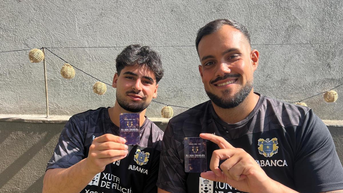 Arnau Fernández y Javi García posan con el carné de socio del Balonmán Cangas.