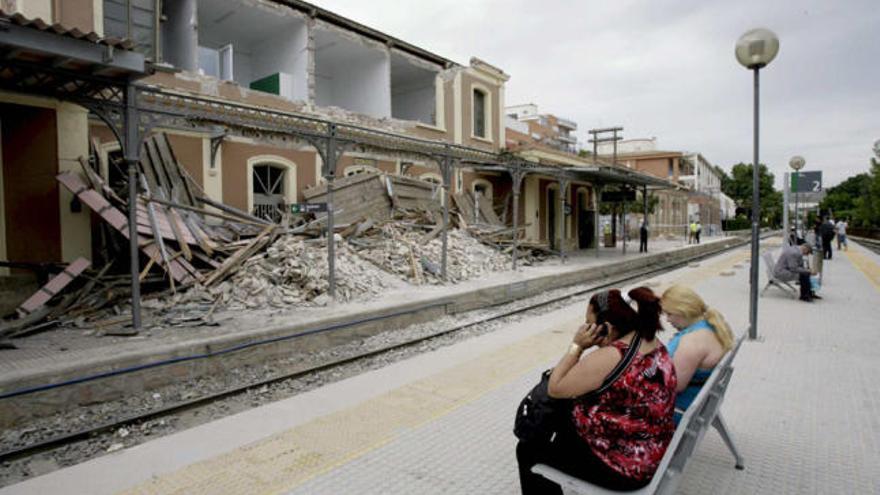 Varias personas esperan el tren en la estación lorquina de Sutullena, que ha resultado muy dañada por el terremoto.