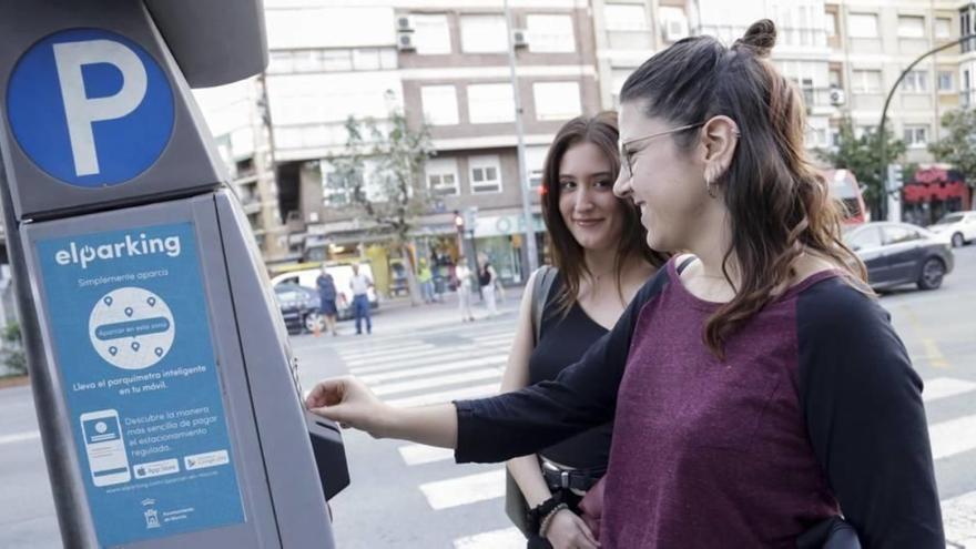 Dos jóvenes echan dinero a la máquina de la ORA