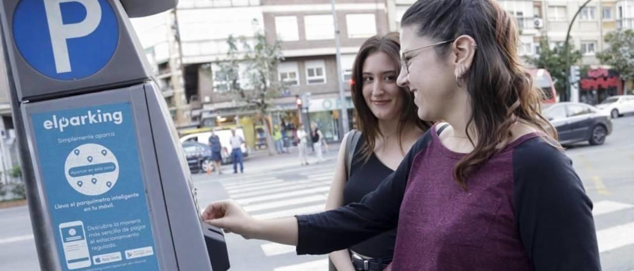 Dos jóvenes echan dinero a la máquina de la ORA