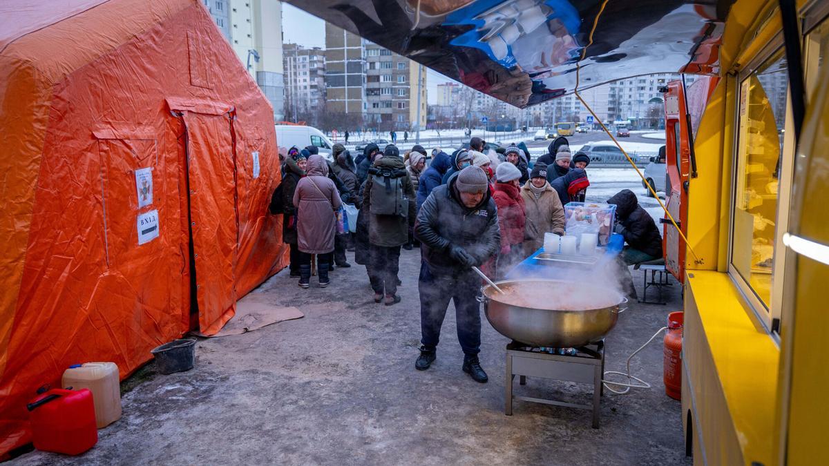 Habitantes de Kiev sin electricidad en casa a causa de los ataques rusos hacen cola para recibir comida caliente en uno de los llamados "puestos de invencibilidad", este viernes en Kiev.