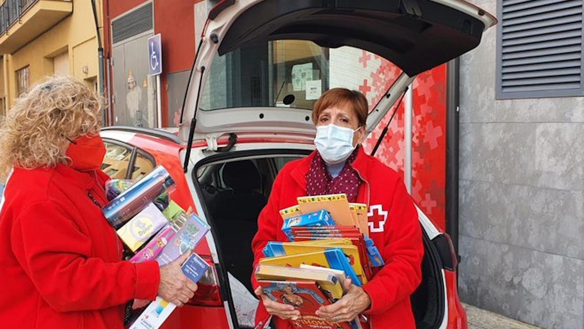 Pla general de dues voluntàries de la Creu Roja repartint regals per a infants en situació vulnerable el 5 de gener de 2022. (Horitzontal)