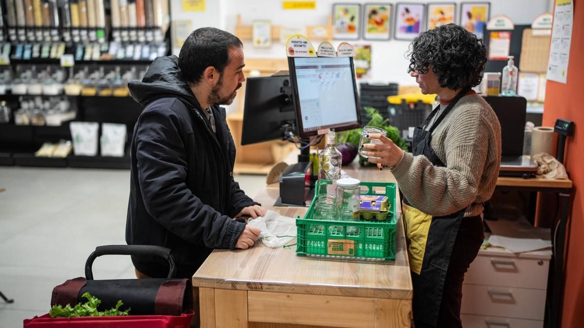 Un cliente compra y devuelve un envase utilizado a un supermercado de la cooperativa Foodcoop BCN