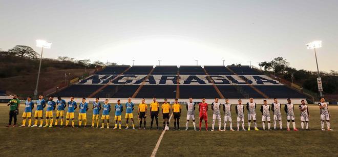 Los jugadores del Managua FC (L) y del Cacique Diriangen FC firman el himno nacional antes de su partido en el Estadio Nacional de Managua. La liga local de fútbol nicaragüense continúa compitiendo a pesar de la pandemia del coronavirus, COVID-19.