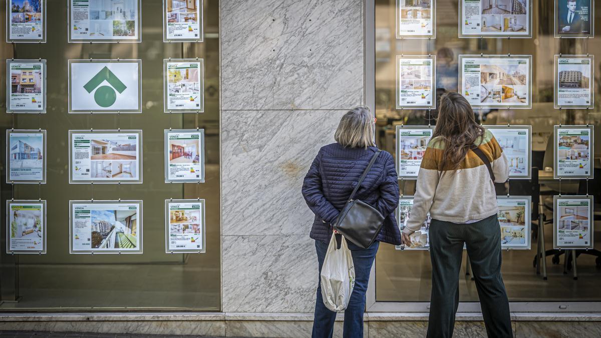 Dos mujeres miran anuncios de pisos en el escaparate de una inmobiliaria de Barcelona.