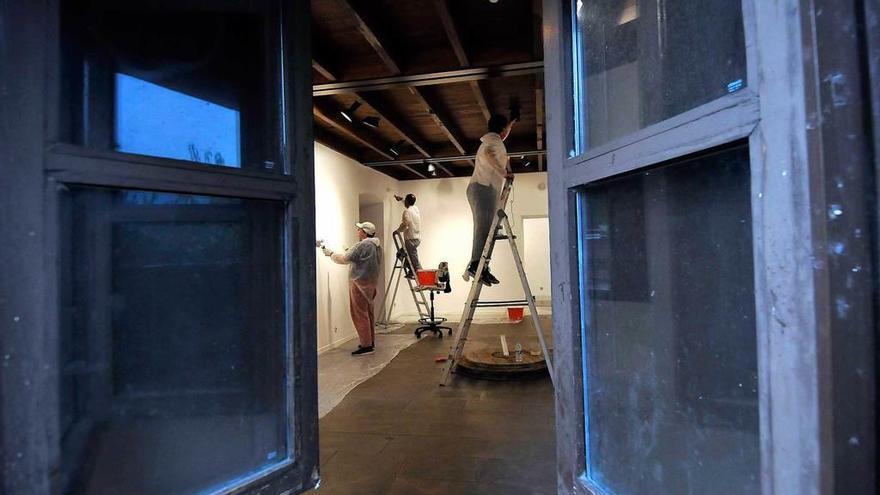 Arriba, varios voluntarios pintan una habitación de la planta baja del edificio. A la izquierda, Juan Antonio Álvarez, con pintura y una brocha.