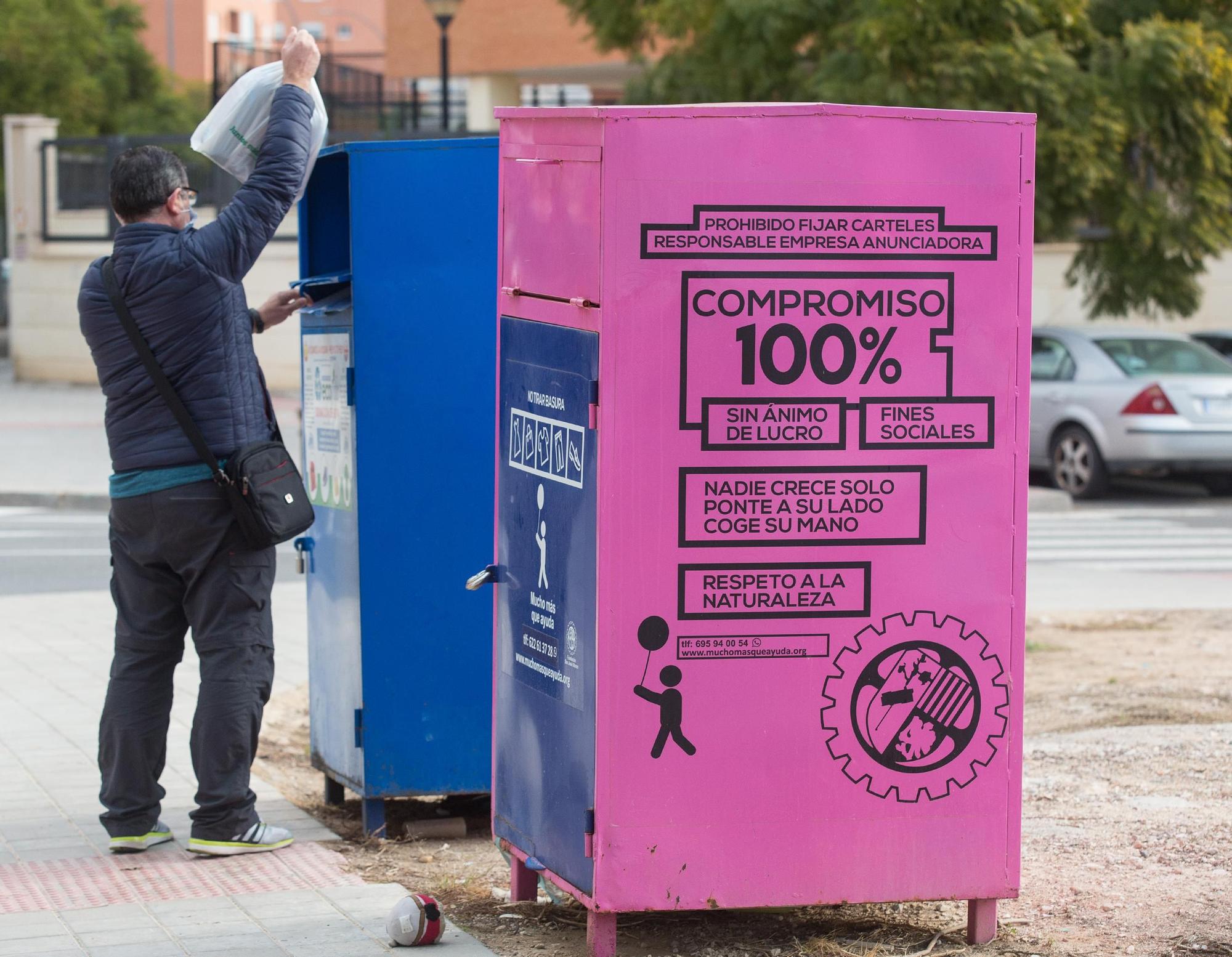 Un ciudadano introduciendo una bolsa en los contenedores destinados a la recogida de ropa en Alicante.