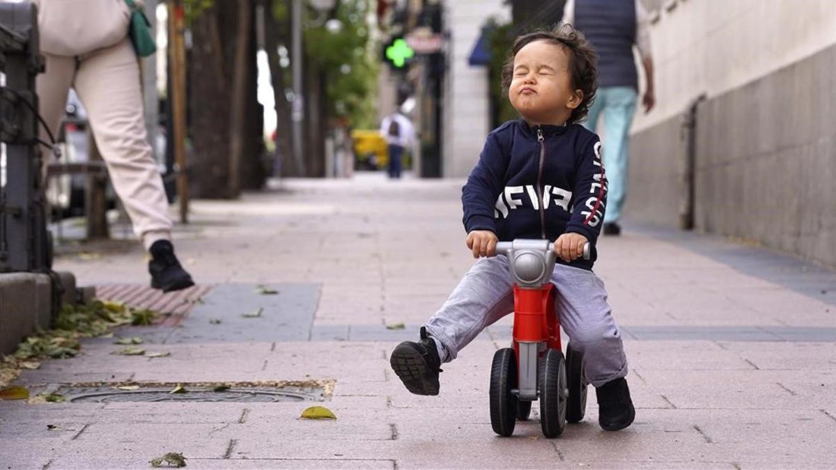 Un niño juega en la calle con su moto durante la hora permitida para los paseos infantiles, esta semana en Madrid.