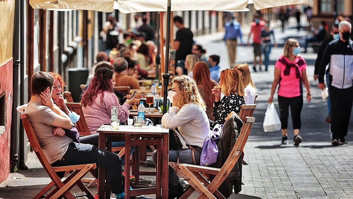 Varios grupos disfrutan de una tarde en la terraza de un bar.