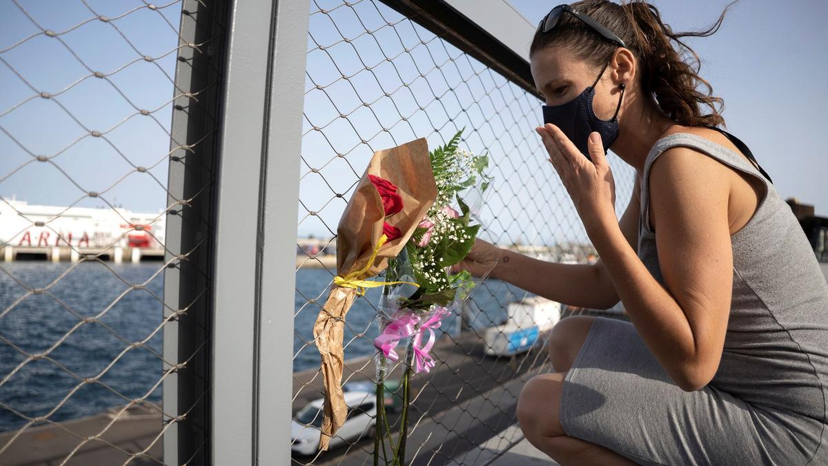 Una mujer deja flores en el puerto de Tenerife.