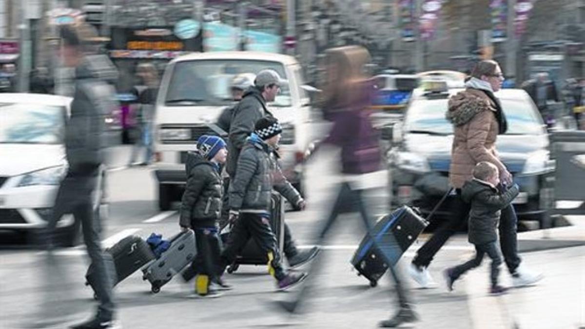 Un grupo de turistas cruzan una calle del centro de Barcelona arrastrando sus maletas, el 26 de diciembre.