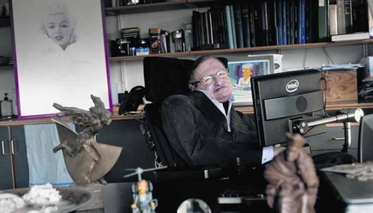 Stephen Hawking, fotografiat al seu despatx de la Universitat de Cambridge. Darrere seu, un retrat de Marilyn Monroe.