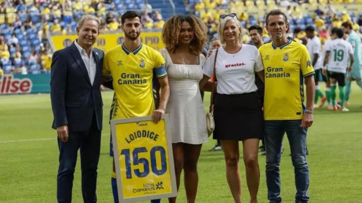 Enzo Loiodice, agasajado por Nicolás Ortega, su pareja y familiares, con el cuadro de los 150 partidos de amarillo.