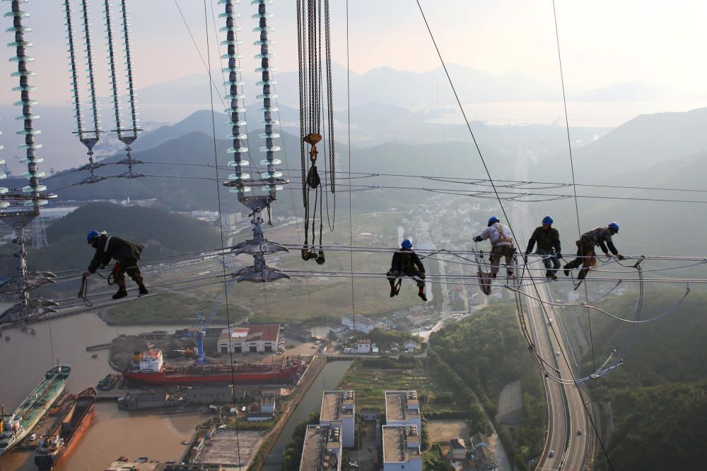 Men work on cables connecting power transmission ...