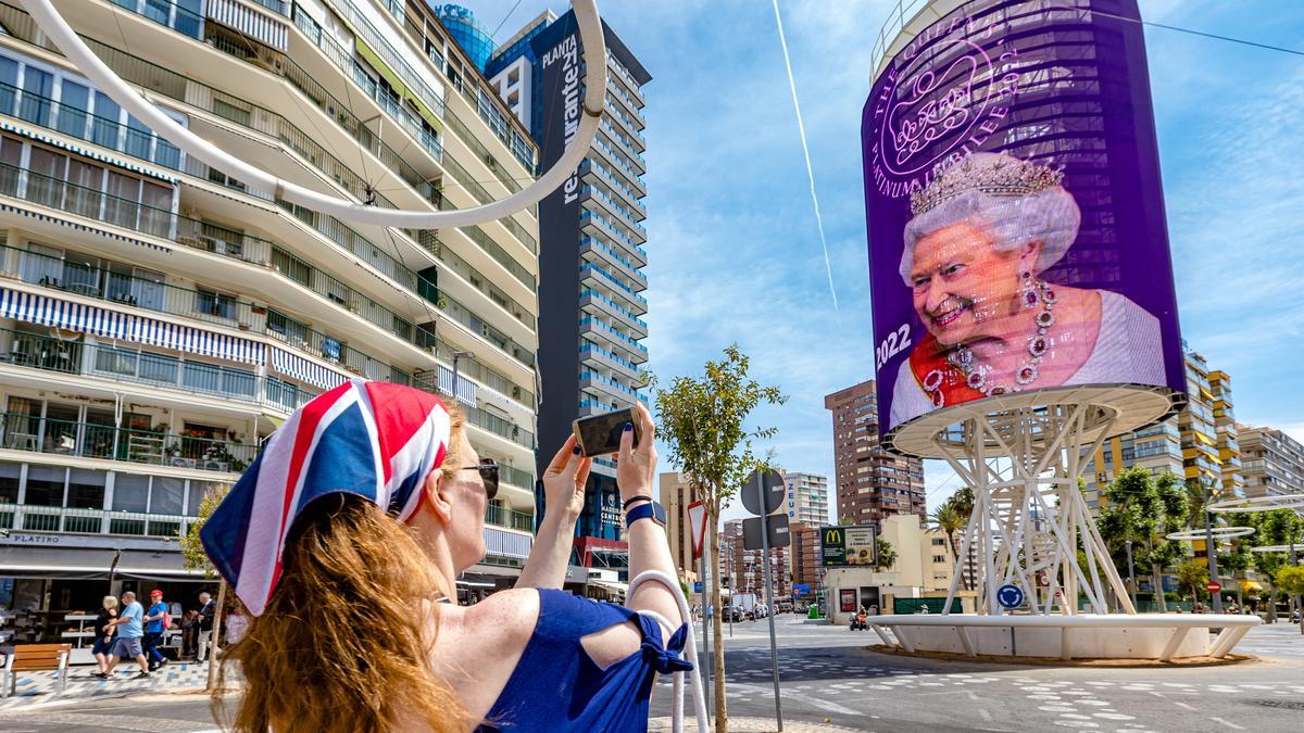 Una turistas fotografía la felicitación por el Jubileo de Platino de la Reina Isabel II en Benidorm.