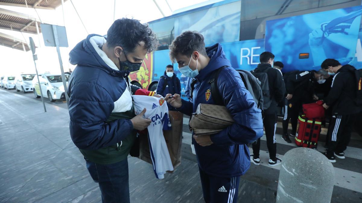 Francés firma la camiseta de un seguidor zaragocista a la llegada de la expedición al aeropuerto para embarcar hacia La Palma.