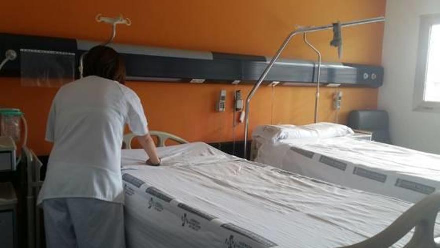 Una enfermera prepara la segunda cama introducida en una habitación individual del hospital.