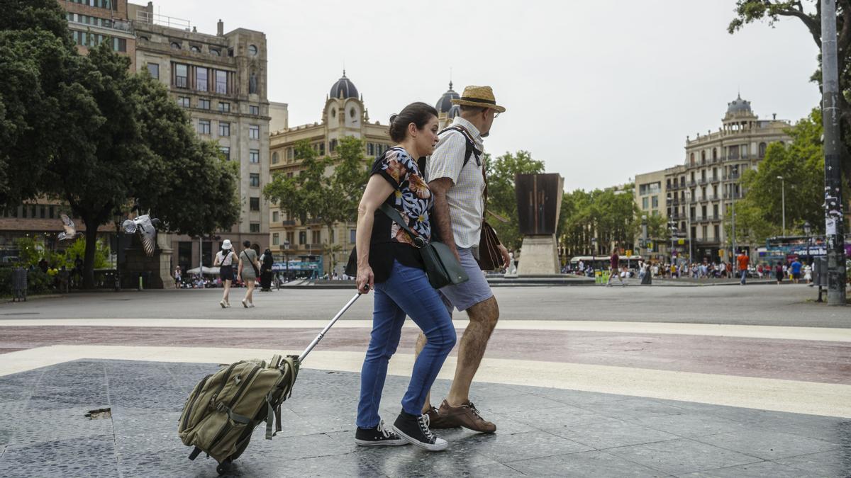 BARCELONA, 28 de junio de 2023: Una pareja de turistas pasea con sus maletas por Plaza Catalunya. Las parejas son el perfil mayoritario del turista en Barcelona. FOTO: Ángel García Martos