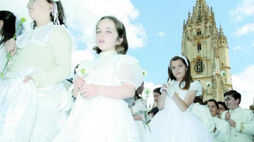 Niños vestidos de primera comunión salen de la Catedral en el inicio de la procesión del día del Corpus.