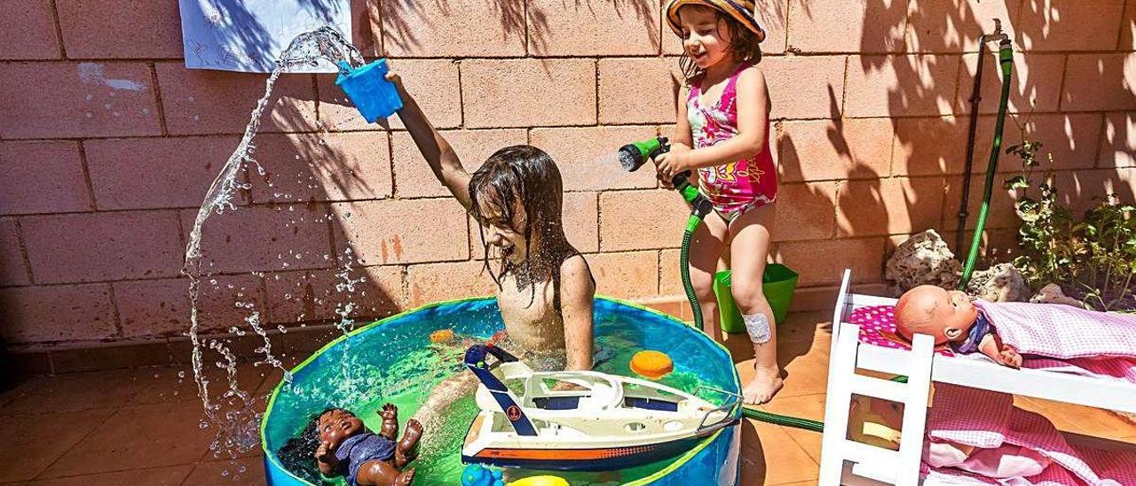 Dos niñas juegan en una piscina hinchable en su casa.