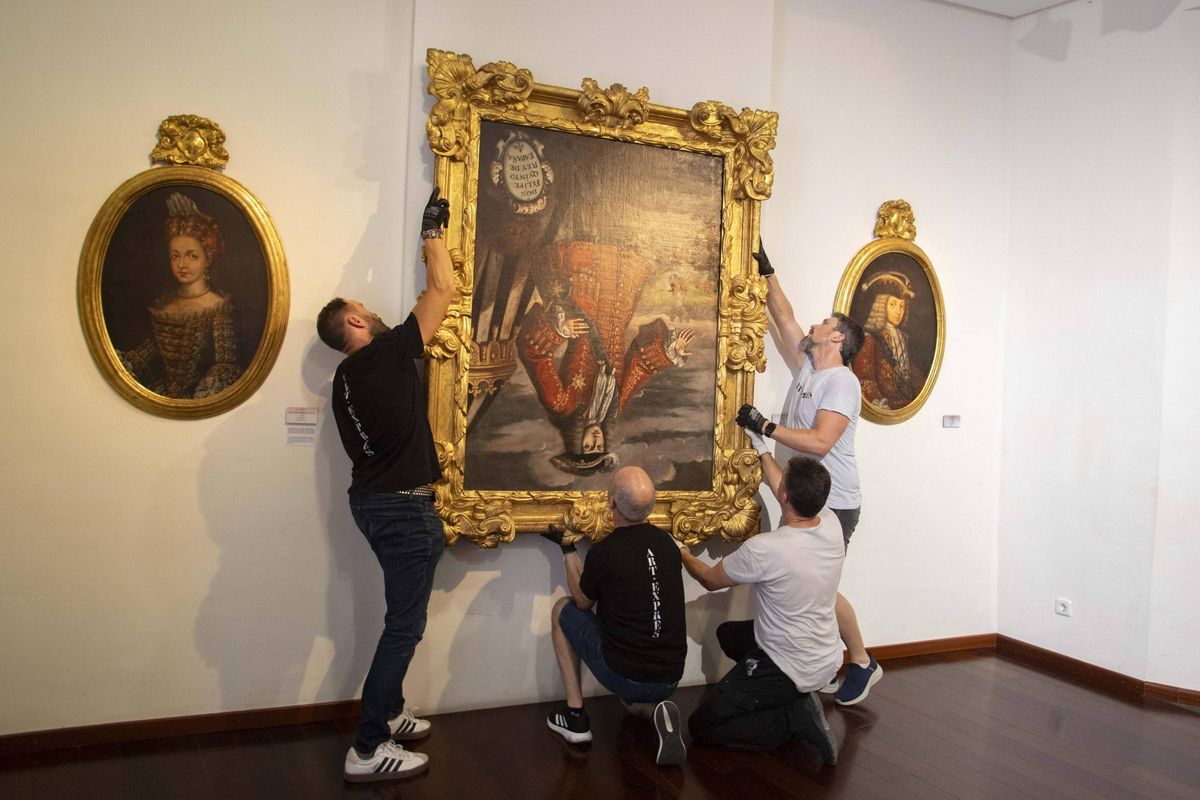 Los técnicos colocando el cuadro de Felipe V boca abajo en el Museu de Belles Arts de Xàtiva.