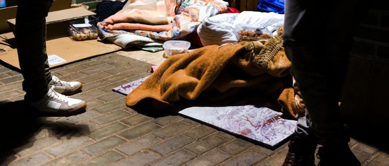 Inmigrantes durmiendo en la calle a la espera de un servicio municipal.