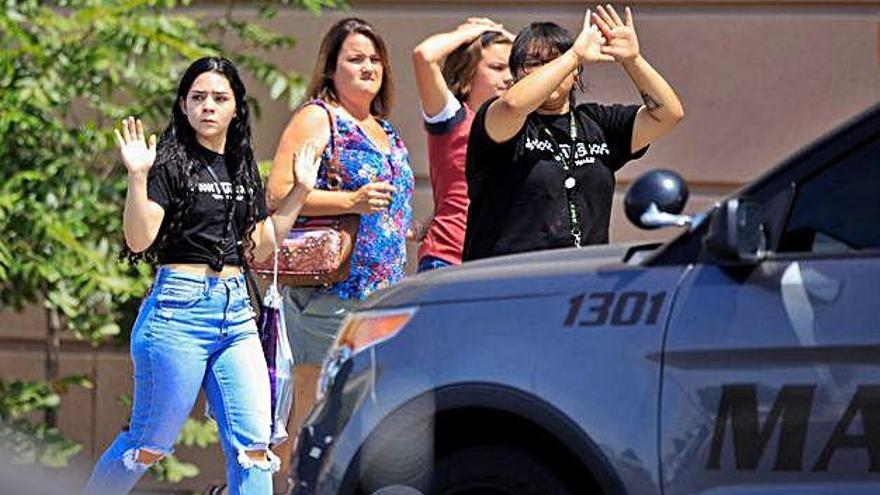 Diverses persones surten del centre comercial atacat a El Paso amb les mans enlaire.