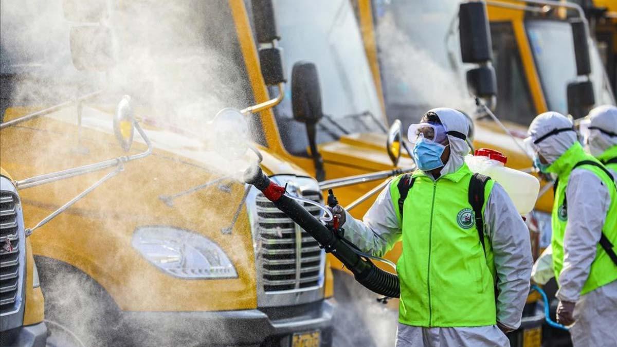 Moncloa aclara que las indicaciones sobre el coronavirus las marca Sanidad. En la foto, Voluntarios desinfectan autobuses escolares en Tengzhou, China. 