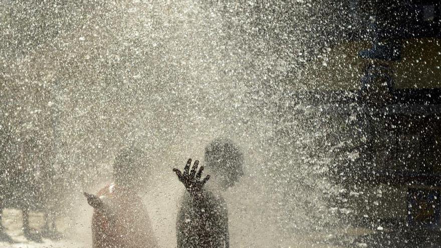 Unos jóvenes se refrescan en una fuente pública