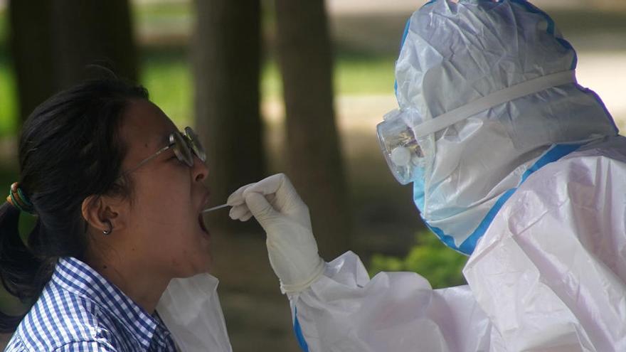 Un trabajador médico con un traje protector realiza un test de coronavirus a una mujer en Beijing.