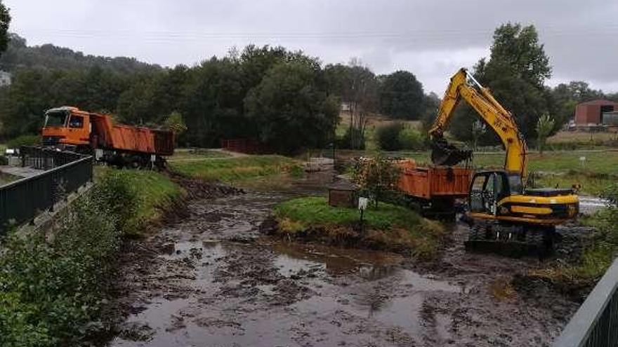 Operarios usando máquinas para limpiar el lago de Rodeiro.