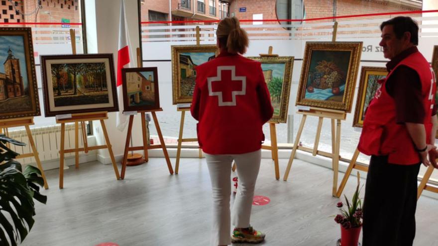 En la imagen de arriba dos integrantes de Cruz Roja visitando la exposición «Trazos» y abajo un momento del acto inaugural con José Manuel del Barrio (izquierda), Inés Mateos (centro) y Luciano Huerga (derecha). | E. P.