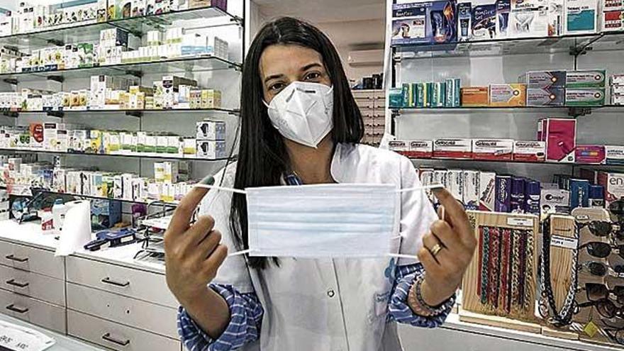 Una farmacéutica muestra una mascarilla quirúrgica.