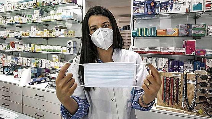 Una farmacÃ©utica muestra una mascarilla quirÃºrgica.