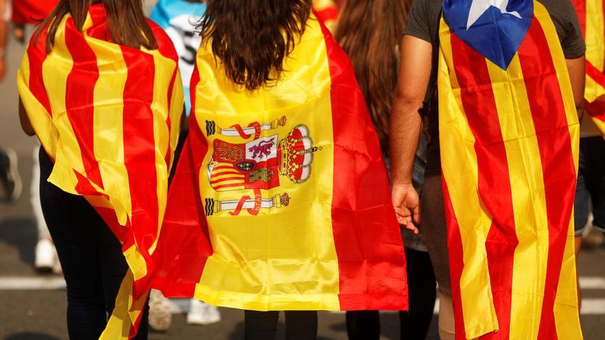 Dos mujeres y un hombre con banderas de Cataluña y de España.