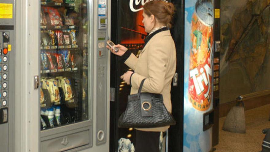 Una mujer paga con el móvil en una máquina dispensadora.