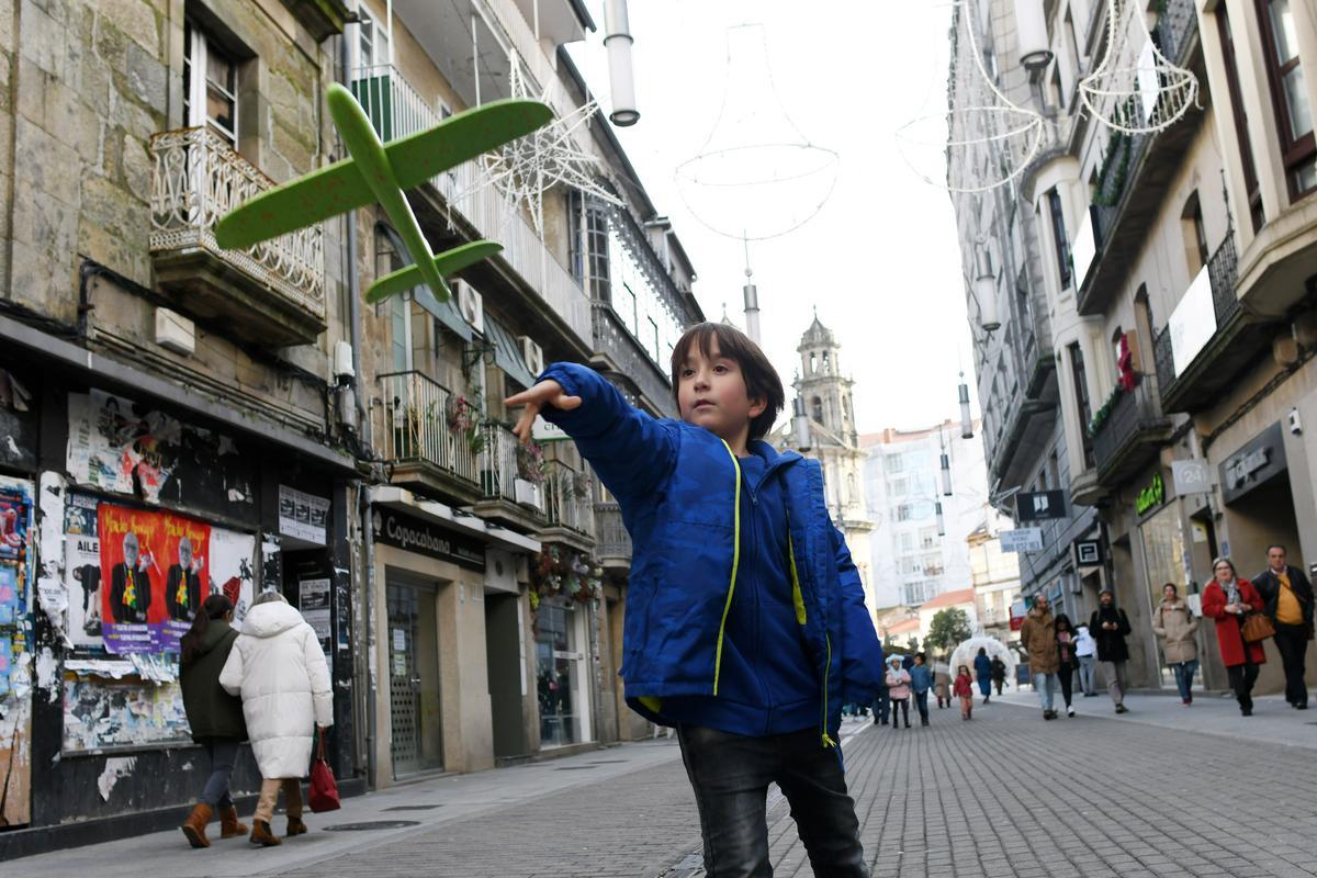 Un niño  lanza su avión nuevo en la calle Michelena.