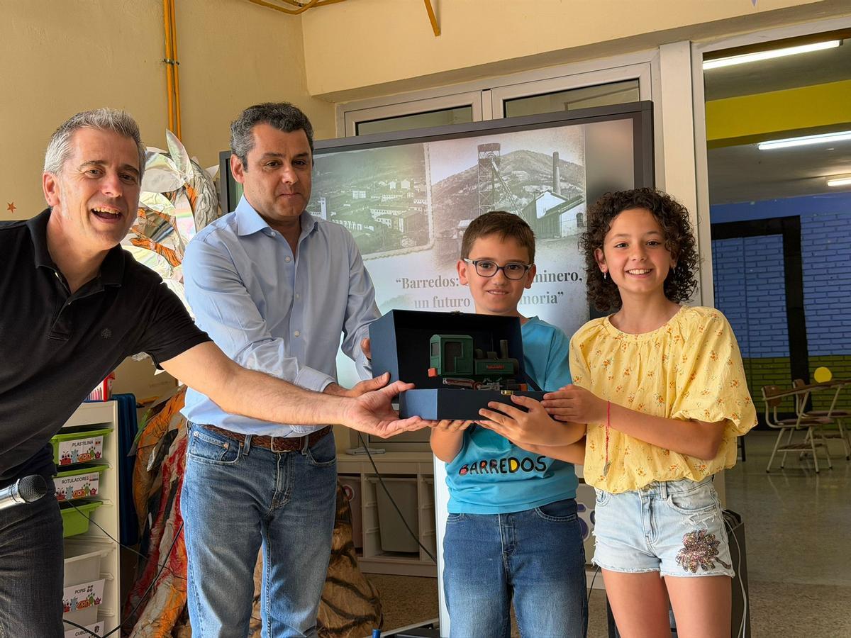 Gustavo Martínez Pañeda, en el centro, entrega la reproducción de una locomotora de Hunosa a los alumnos del colegio de Barredos