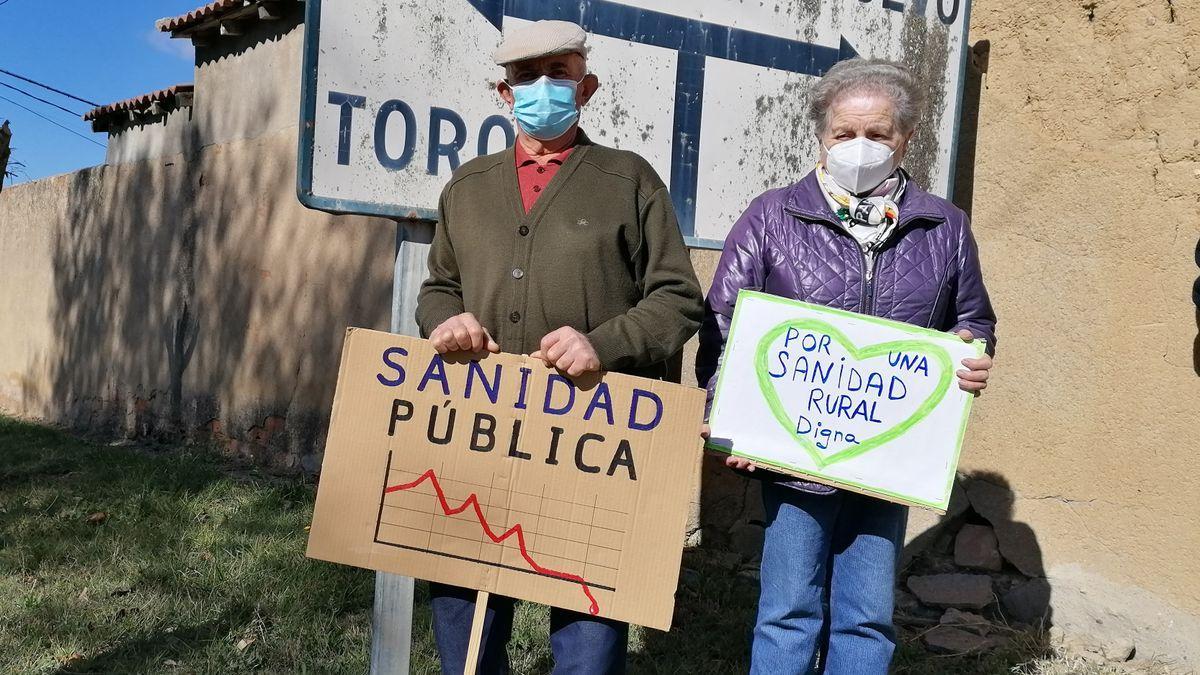 Dos vecinos de Pozoantiguo (Zamora) muestran pancartas de protesta contra las carencias de la Sanidad Pública