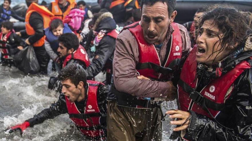 Refugiados saltan de una lancha tras lograr alcanzar la costa griega.