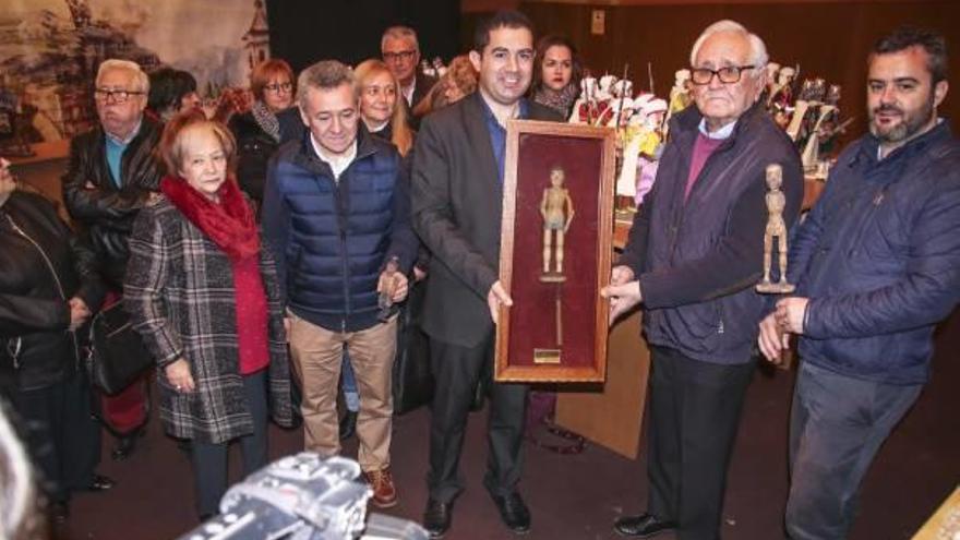 El alcalde sostiene la urna que contiene la antigua figura del Tirisiti junto a los componentes de la familia Peidro y el edil de Cultura.