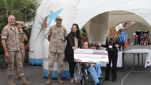 En la imagen superior, representates de APEM recogen el donativo de la carrera. Debajo, la vencedora en la modalidad Medium, Esther Arias.