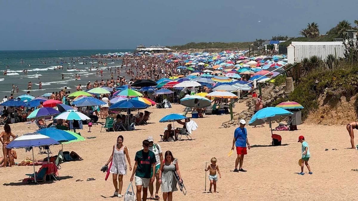Imagen de una playa de Chipiona llena de sombrillas y bañistas este verano. ARCHIVO.