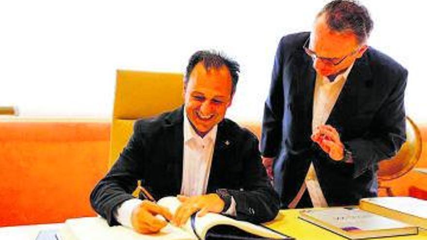 Llorenç Córdoba firma en el libro de honor junto a Javier Moll.