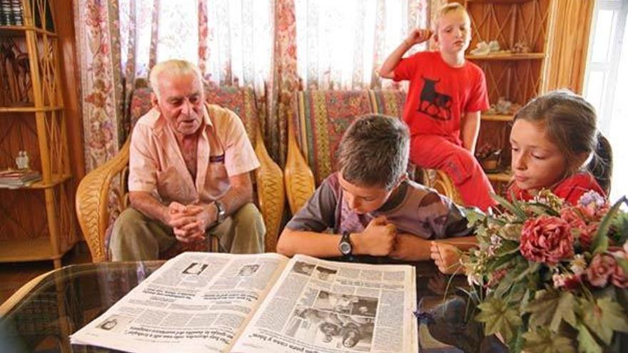 Manuel García, con sus nietos y un amigo de éstos, en su casa de Pedornes, leyendo FARO.  // Carlos Pereira