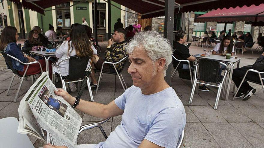 El cliente de un bar lee LA NUEVA ESPAÑA en una terraza de Laviana, donde ya se acordó la exención del pago de esta tasa.